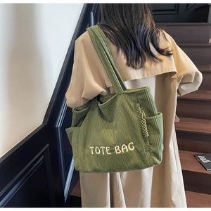 Gros plan du sac cabas en velours côtelé vert montrant la texture rayée et la broderie
