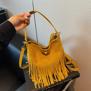 Detail of yellow suede bucket bag featuring long fringe and golden metal twist lock