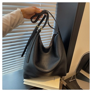 Close-up of black litchi grain leather hobo bag with adjustable strap and gold buckle