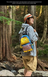 Outdoor shot showing vibrant color-block backpack with orange bungee cords in a forest