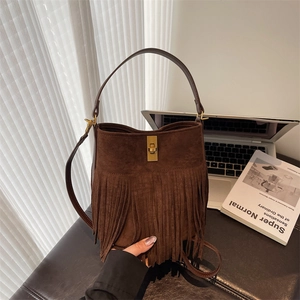 Detail of dark brown suede bucket bag featuring long fringe and gold metal twist lock
