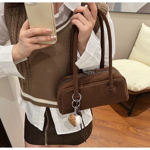Brown suede shoulder bag with top zipper and baseball charm shown on model