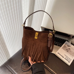 Detailed view of brown suede tassel bucket bag with gold twist lock and retro fringe style