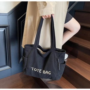 Détail du grand sac cabas en velours côtelé noir avec broderie blanche et poche latérale