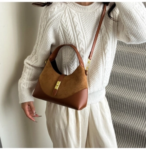 Close-up of brown suede and leather contrast handbag with elegant gold metal buckle