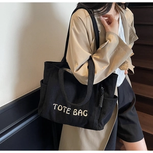 Détail du sac cabas en velours côtelé noir montrant le tissu et le logo brodé blanc