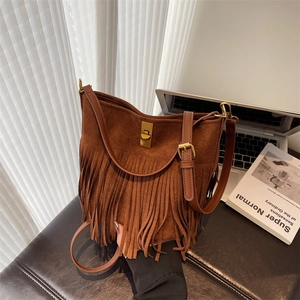 Detailed close-up of brown suede bucket bag with long tassels and gold metal turn-lock closure