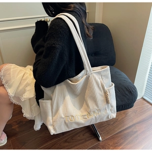Détail du sac fourre-tout en velours côtelé beige avec broderie et texture du tissu