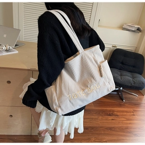 Gros plan du sac cabas en velours côtelé beige avec broderie TOTE BAG et poches