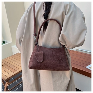 Detail of dark brown suede shoulder bag with minimalist design and side pendant decoration