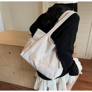 Détail du cabas en velours côtelé blanc cassé avec broderie TOTE BAG et bandoulières