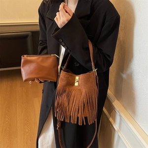 Detail of retro fringed bucket bag with matte suede texture and gold twist lock closure