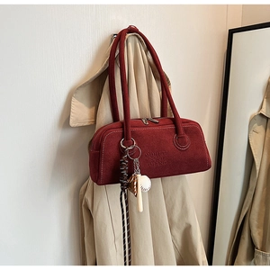 Detail of red suede Boston bag with leather handles and baseball charm ornament