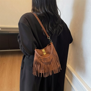 Detail of brown suede crossbody bag featuring long fringes and a gold metal buckle lock