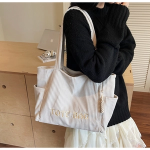 Détail du cabas en velours côtelé beige avec broderie et poche latérale zippée robuste