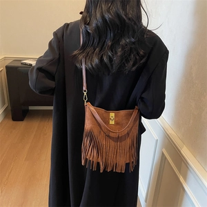 Detailed view of brown fringe crossbody bag with suede texture and gold twist-lock closure