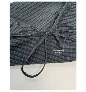 Detail of grey checkered fabric with adjustable drawstring knot on a casual shoulder bag