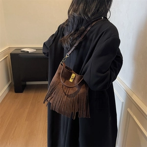 Close-up of retro brown suede bucket bag with long tassels and metallic buckle detail
