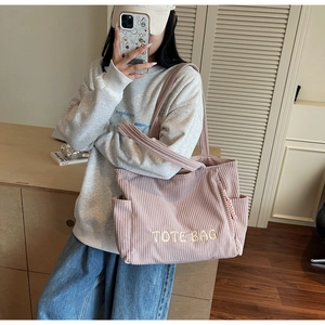 Détail du sac cabas en velours côtelé rose avec broderie blanche et poche latérale