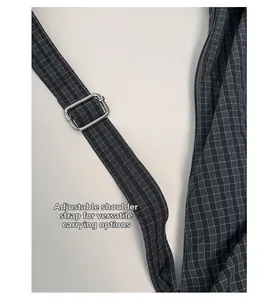 Detail of adjustable shoulder strap with silver buckle and fine grey plaid fabric