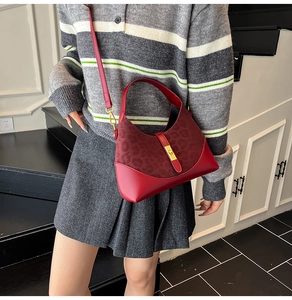 Detail of red leather hobo bag with leopard print panel and gold metal buckle worn cross-body