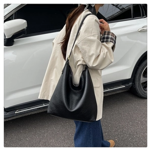 Outdoor model shot of black pebble leather tote bag showing large capacity and soft structure
