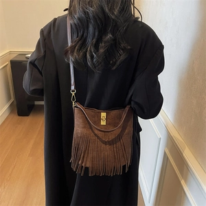 Close-up of brown suede bucket bag featuring long fringe tassels and golden metal clasp