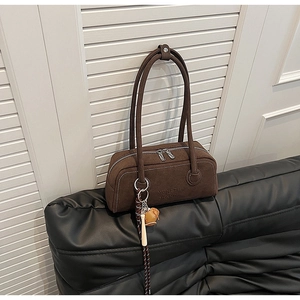 Detail of dark brown matte suede Boston bag with double silver zippers and bear charm