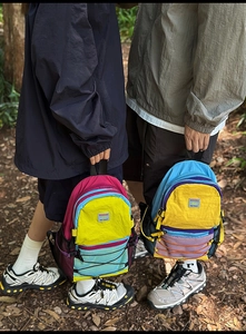 Detail of colorful hiking backpacks with contrast panels and bungee cords in outdoor forest