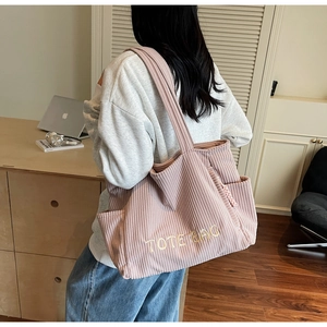 Détail de sac cabas en velours côtelé rose avec broderie et poche latérale pratique