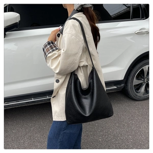 Close-up of black lychee texture leather tote bag worn on shoulder for daily commute