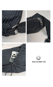 Detail of plaid crescent bag featuring durable metal zipper and adjustable silver buckle