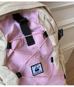 Detail of pink outdoor backpack with elastic cord and penguin brand label on nylon fabric