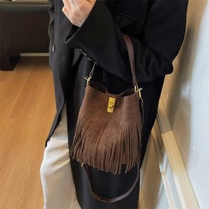 Detail of vintage brown suede bucket bag with fringe tassels and gold twist lock