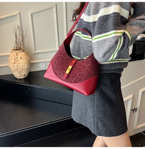 Detail of red leather and leopard print patchwork bag with a golden turn-lock closure