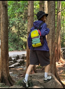 Outdoor color-block backpack detail featuring functional bungee cords and multi-tone panels