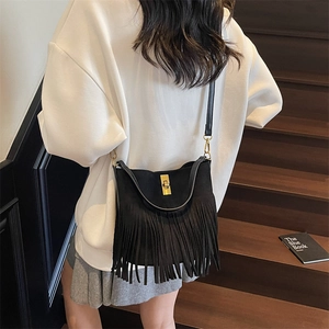Detail of black suede crossbody bag showing long tassels and golden metal lock