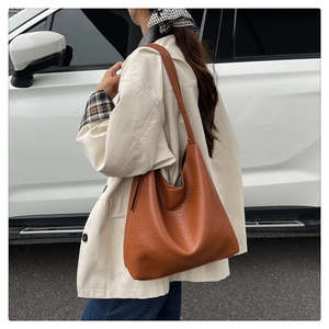 Outdoor shot of a large brown tote bag with litchi texture on a female model