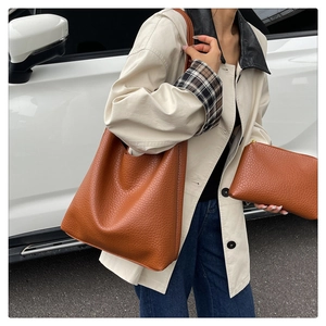Brown lychee leather bucket tote bag and small pouch set on model in beige coat