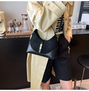 Detail of black leather and suede bag with gold lock shown in a cafe setting