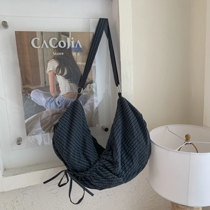 Detail of dark grey checkered hobo bag with drawstring texture and adjustable strap