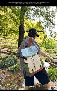 Outdoor backpack with color-block design shown against a scenic forest stream backdrop
