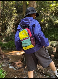 Close-up of colorful patchwork hiking backpack with bungee cord detail in forest setting