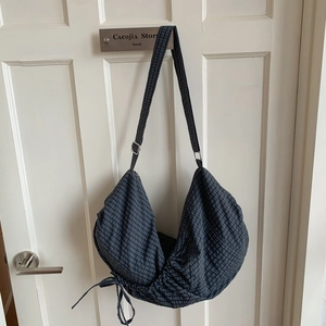 Detail of navy blue checkered hobo bag with drawstring and adjustable shoulder strap