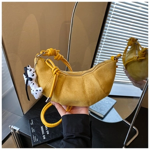 Detail of ginger yellow crescent bag with knotted strap and dalmatian dog charm accessory