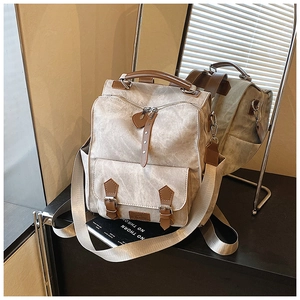 Detail showing vintage beige canvas backpack with brown leather straps and multi-strap design