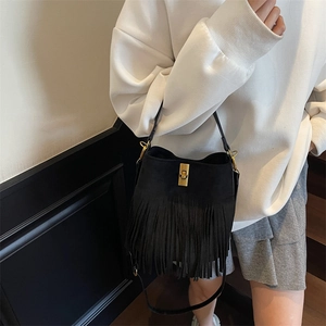 Close-up of black suede bucket bag with fringe tassels and a golden twist lock