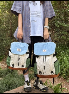 Detail of color-block outdoor backpacks with drawstring closure in a natural forest setting