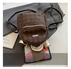 Détail d'un mini sac à dos à damier marron montrant l'espace pour tablette et cosmétiques