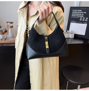 Close-up of black mixed-material handbag featuring suede textures and gold metal clasp